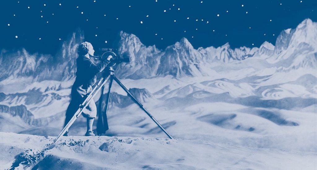 The image is a picture used for The Moon's event poster. A blue moon landscape and a person with an instrument observing and photographing the surroundings.