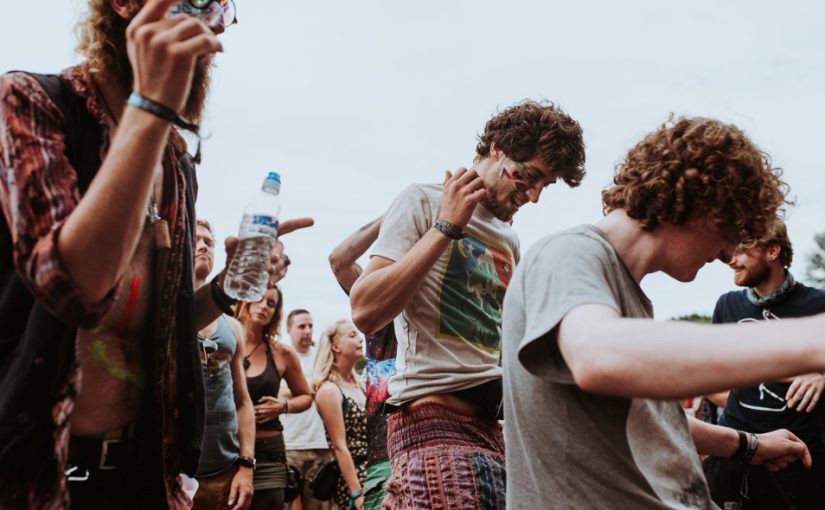 Billedet viser en gruppe festivalgængere, der danser under åben himmel. Foto: Stephen Arnold/Unsplash.