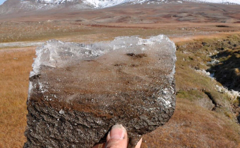 Et stykke permafrost holdt op mod landskab i Grønland