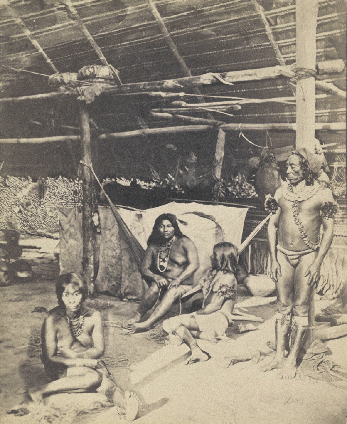 Three half-naked women and a half-naked man in a hut.